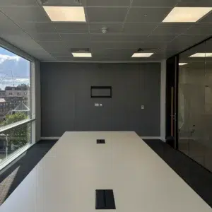 Meeting room with glazed grid partition, entrance door and acoustic wall panel in a commercial office fit-out